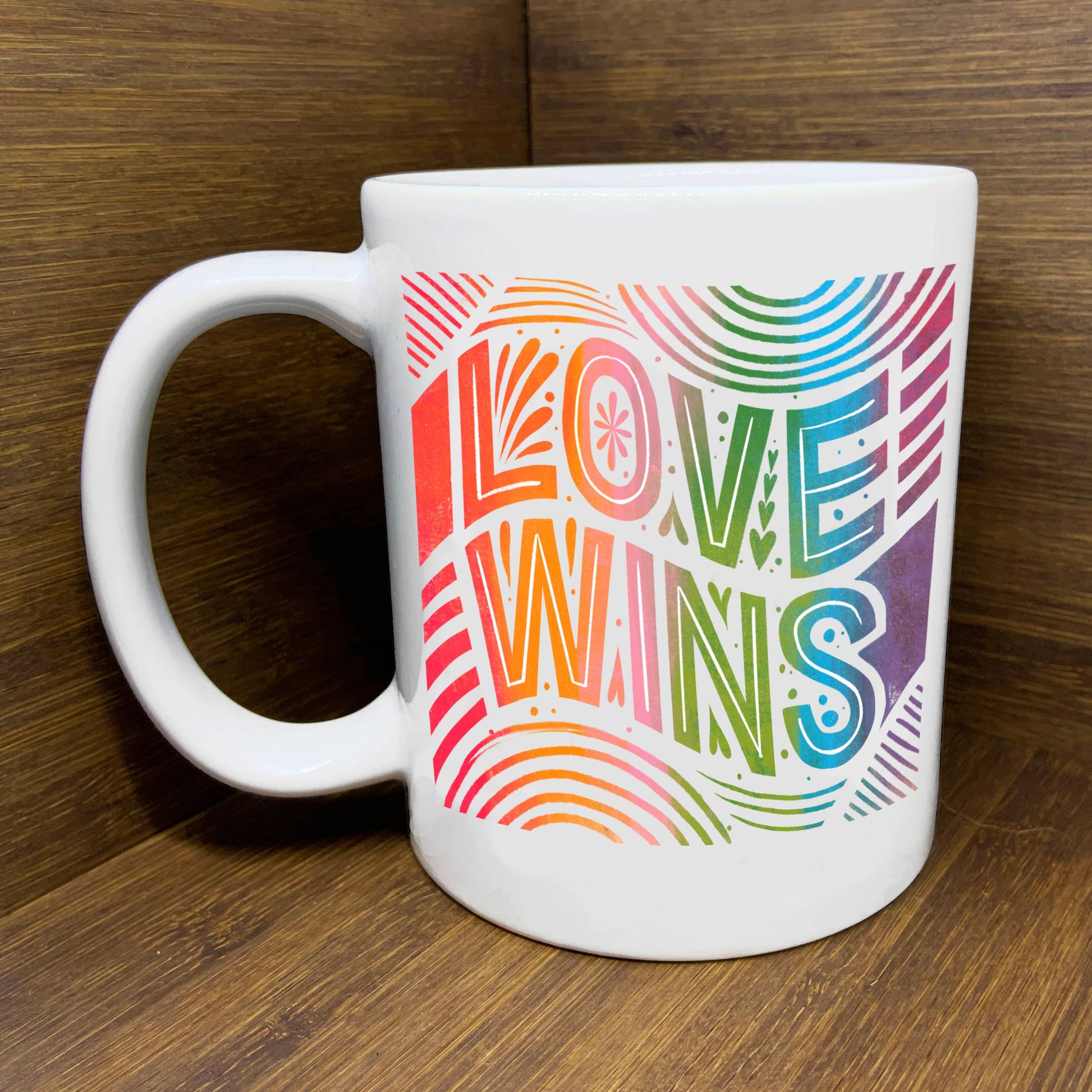 Love Wins mug with rainbow ombre art displayed on a wooden surface