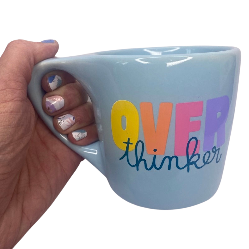 hand holding the colorful over thinker light blue mood mug for coffee or tea