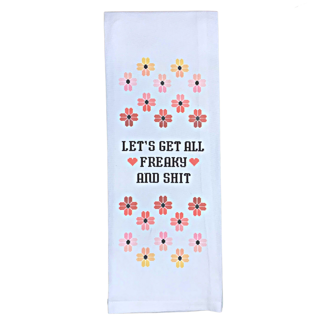 premium quality pre-shrunk hand kitchen towel that is white and says let's get freaky and shit with old school cross stitch flower design above and below 